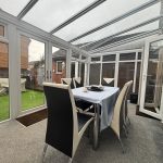 Modern conservatory dining area with glass roof.