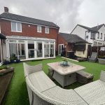 Spacious garden with furniture and modern conservatory.