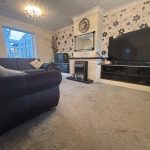 Modern living room with sofa, TV, and fireplace.