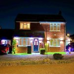 Illuminated house facade with cars at night.