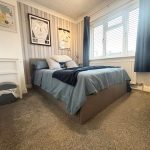 Cosy bedroom with framed shirts and window blinds.