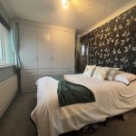 Cosy bedroom with floral wallpaper and wardrobe.