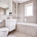 Modern bathroom with bath, sink, toilet, and window.