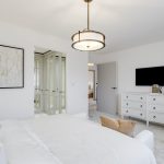 Modern white bedroom with dresser and artwork.