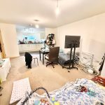 Living room with TV, desk, and kitchen area.