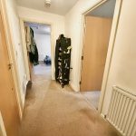 Carpeted hallway leading to rooms in a house.
