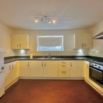 Modern kitchen with wooden floor and appliances.