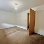 Empty bedroom with carpet and open door.