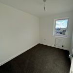 Empty room with window and dark carpet floor.