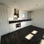 Modern kitchen with wooden cabinets and dark floor.