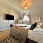 Stylish cosy bedroom with chandelier and TV.