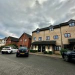 Terraced houses on cloudy day with parked cars.