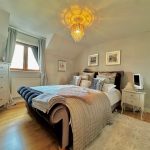 Cosy bedroom with elegant decor and chandelier lighting.