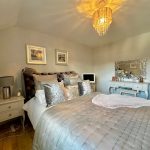 Elegant bedroom with chandelier and decorative pillows.