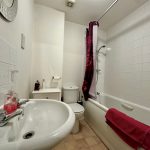 Modern bathroom with sink, toilet, shower and red accents.