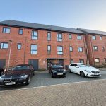 Three cars parked outside red brick building.
