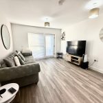 Modern living room with grey sofa and large TV.