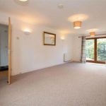 Spacious living room with carpet and large window.