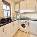 Compact kitchen with washing machine and window view.