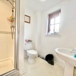 Bright bathroom with shower, toilet, and sink.