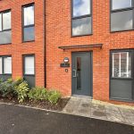Modern brick building with grey door and windows.