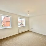 Empty room with carpet and two windows.