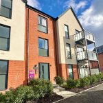 Modern apartment building with balconies and greenery.