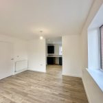 Spacious open-plan room with wooden flooring.