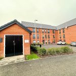 Modern brick building with parking area and cars.