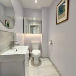 Modern bathroom with mirror and artwork.