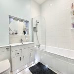 Modern white bathroom with sink, toilet, and bath.