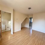 Empty room with wooden flooring and open door.