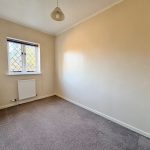 Small empty room with window and beige walls.