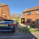 Brick house with car parked in driveway.