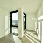 Bright empty room with large window and wood floor.