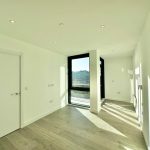 Bright empty room with large window, wooden floor.