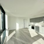Bright modern kitchen with large windows and grey units.
