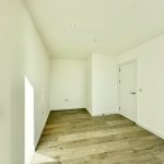 Minimalist empty room with wooden floor and white walls.