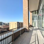 Modern balcony with city view, sunny day.