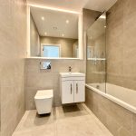 Modern bathroom with beige tiles and fixtures.