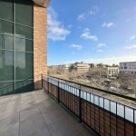 Sunny balcony overlooking modern office buildings.