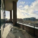 Sunny urban balcony view with modern buildings.