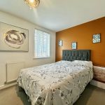 Modern bedroom with orange accent wall and floral decor.