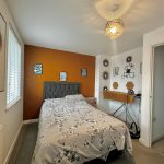 Modern bedroom with orange accent wall and decor.