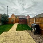 Back garden with paving, grass, and barbecue grill.