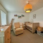 Cosy nursery with crib, chair, and giraffe decor.