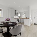 Modern kitchen with dining area and wooden flooring.