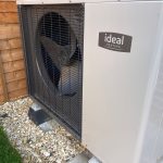 Outdoor heat pump unit near wooden fence