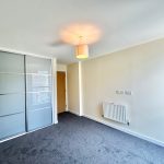 Bright empty room with sliding wardrobe and radiator.