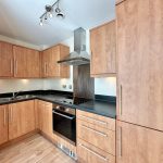 Modern wooden kitchen with built-in oven and hob.